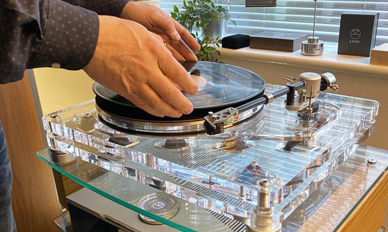 Vertere MG-1 MKII Turntable with a man placing a record on it.